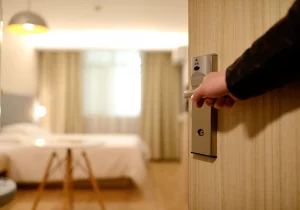 main qui ouvre la porte d'une chambre d'hôtel, visible en arrière plan