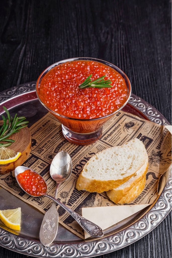 caviar rouge dans une coupelle, sur un plateau, servi avec du pain