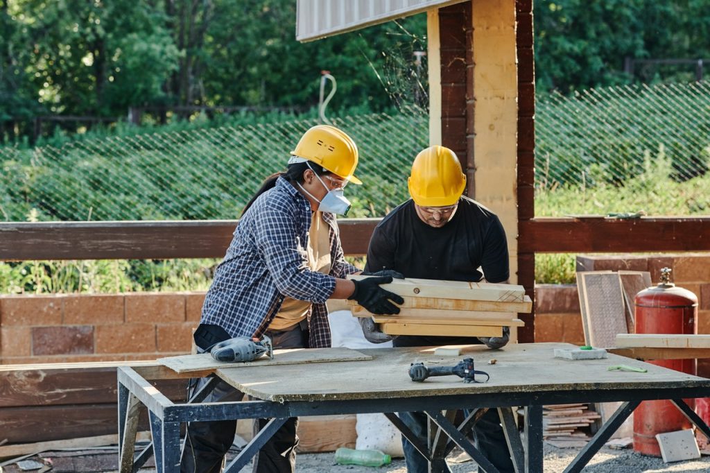 deux ouvriers qui travaillent le bois sur un plan de travail